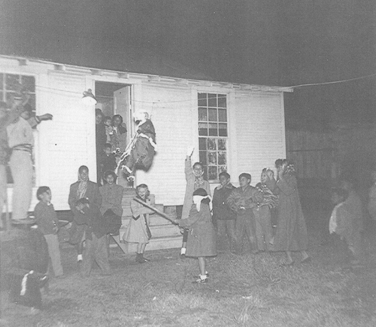 Children outside the Boettcher residence attempting to break a piñata.
