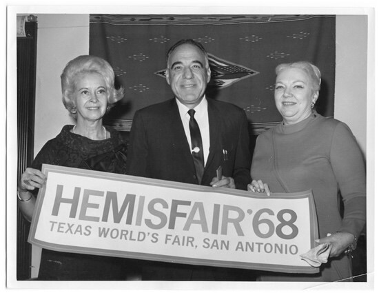 Congressman Henry B. Gonzalez, standing between two unidentified women, holding a banner with the text "HemisFair '68. Texas World's Fair, San Antonio." 